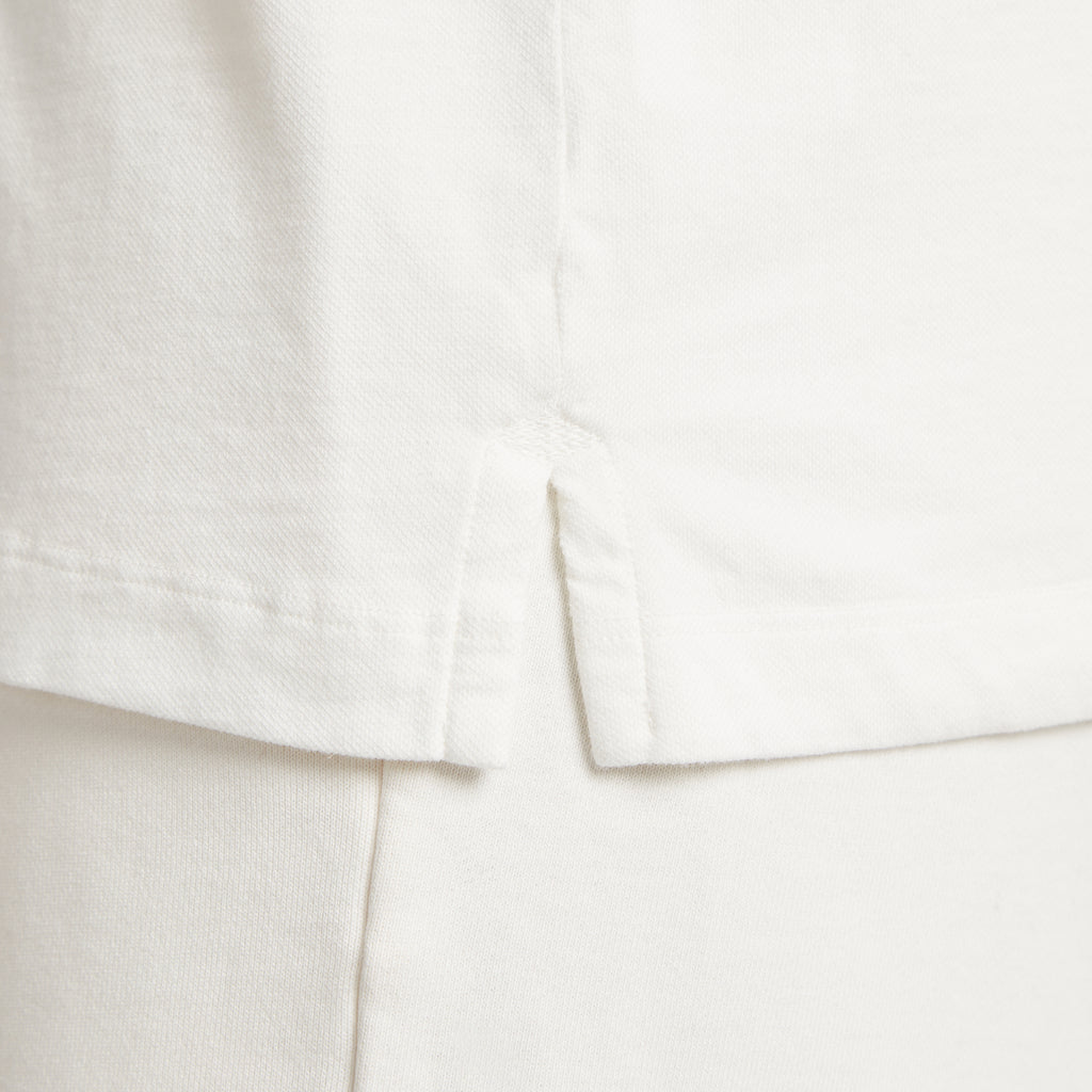 Dettaglio tessuto micro piquet bianco, cuciture precise e finiture premium uomo