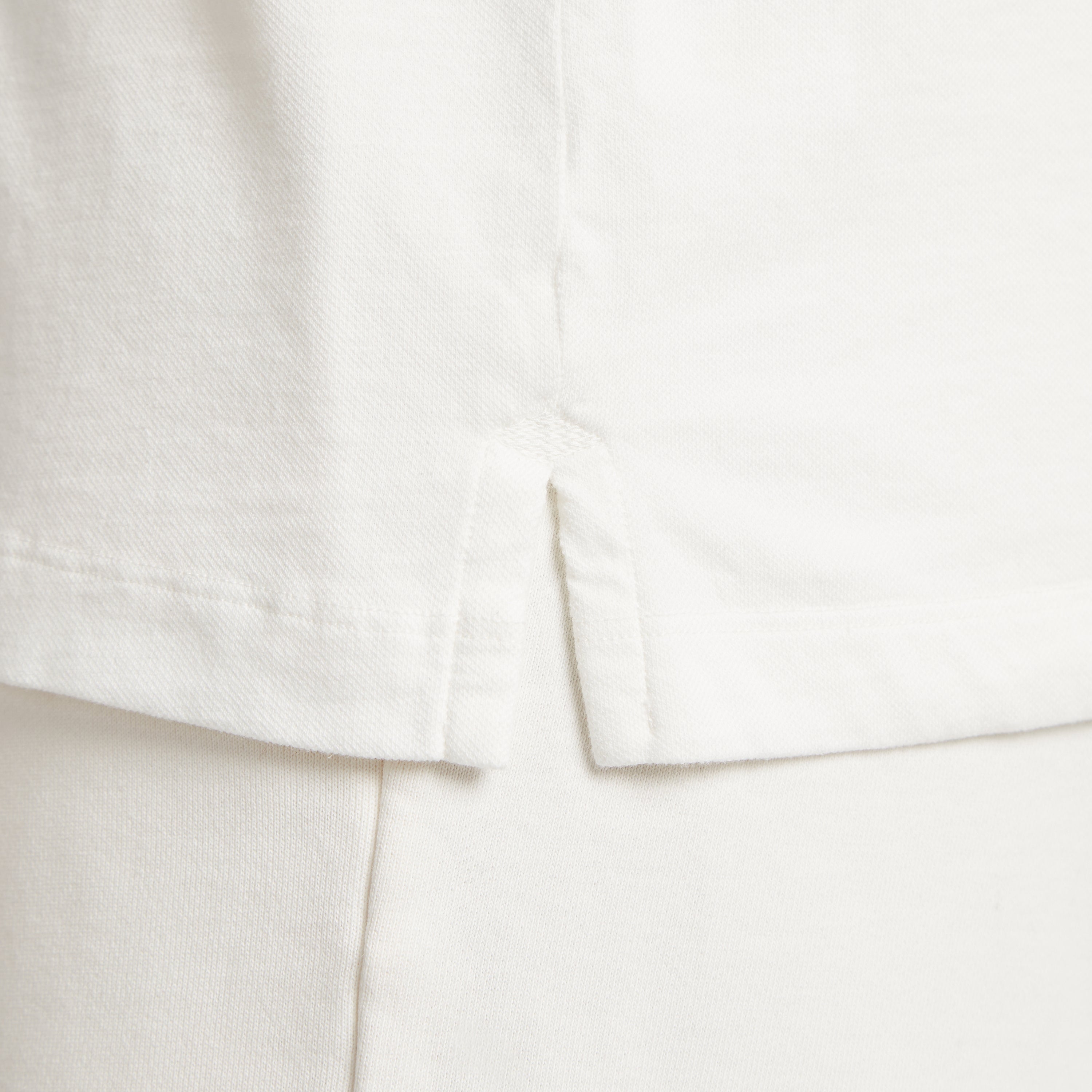 Dettaglio tessuto micro piquet bianco, cuciture precise e finiture premium uomo